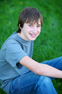 photo of boy with braces sitting in grass